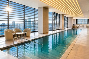 Ein moderner, überdachter Pool mit Panoramafenstern, einer Liegefläche am Pool und Blick auf die Stadt.