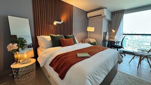 Una habitación de hotel moderna con una cama grande, mesita de noche, lámpara y vista a la ciudad.