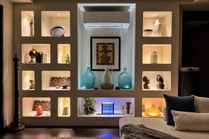 A modern living room with a central air conditioning unit, multiple shelves with decorative items, and a sofa with cushions. - 500Mbps | Sit-Stand Desk | Pro-Kitchen | WD | King (Makati City)
