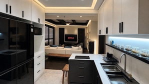 Een moderne keuken met een ingebouwde oven, een eethoek met een tafel en stoelen, en een woonkamer met een bank en een televisie waarop 'NETFLIX' wordt weergegeven.