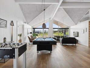 A modern indoor space with a pool table, seating area, and a view of the outdoors. - 5 Star Holiday Home in Idestrup (Idestrup)