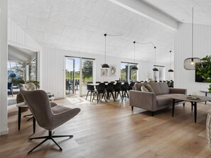 A spacious living area with a dining table, chairs, and a sofa. - 5 Star Holiday Home in Idestrup (Idestrup)