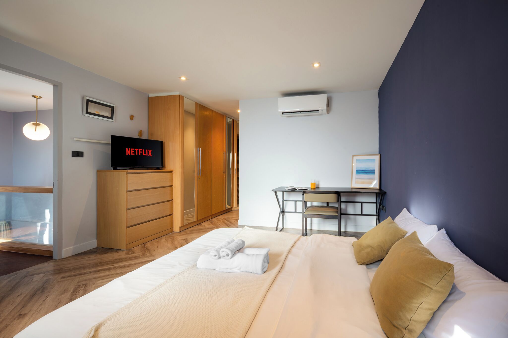 Une chambre d’hôtel moderne équipée d’un lit, d’un bureau, d’une armoire et d’un appareil de climatisation.