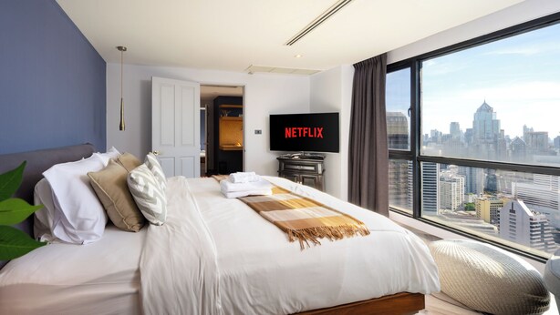Una habitación de hotel moderna con una cama grande, televisión y vistas a la ciudad.