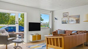 A modern living room with a sofa, a TV, a desk, and a chair. - "Aderice" - 80m from the sea by Interhome (Haderslev)