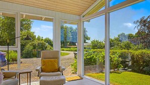 A conservatory with a chair and table, large windows, and a view of a garden. - "Aderice" - 80m from the sea by Interhome (Haderslev)