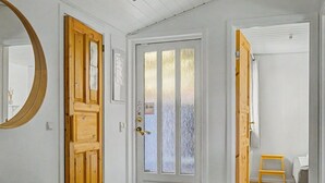 A hallway with a wooden door, a mirror, and a small wooden table. - "Aderice" - 80m from the sea by Interhome (Haderslev)