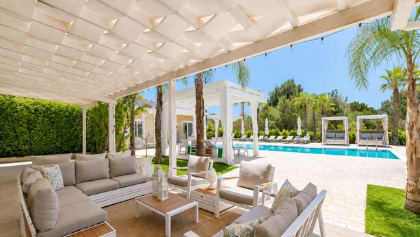 A covered outdoor seating area with a pool, lounge chairs, and a dining table. - Villa Rudiae by Symphonya Rentals (Lequile)
