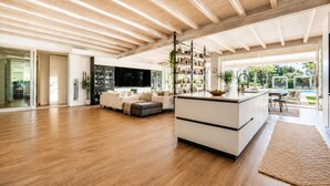 A spacious living area with a wooden floor, a sofa set, a kitchen island, and a view of the outdoors. - Villa Rudiae by Symphonya Rentals (Lequile)