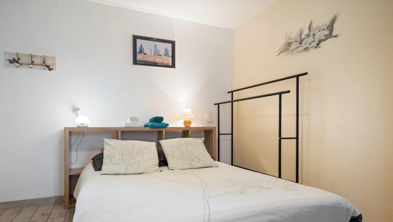 Een slaapkamer met een bed, bedlampen, een nachtkastje van hout en een inbouwkleerkast.