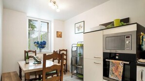 A compact kitchen with a dining table, chairs, a refrigerator, and a microwave.