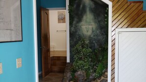 Una escalera de madera con peldaños que conduce a un rellano, una pared azul y un suelo de baldosas.