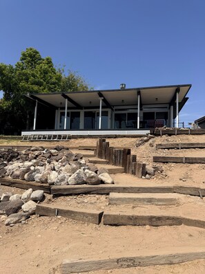 A building with a covered porch, large windows, and a stone foundation.