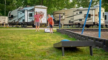 Zona verde con vehículos recreativos y un parque infantil.