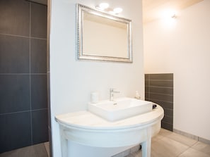 Un baño con un lavamanos blanco, un espejo con marco decorativo e iluminación en la pared.