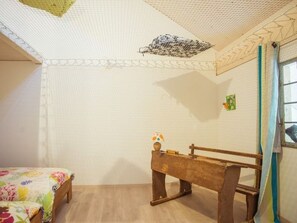 Una habitación con una cama, un banco de madera y una pequeña mesa con una lámpara.