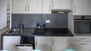 A modern kitchen with grey cabinets, a stainless steel sink, a built-in oven, and a dishwasher. - Gîtes - La Clef des Franches, (Saignelegier), by Interhome (Saignelegier)