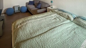 A bedroom with a sloped ceiling, a bed, a sofa, a small table, and a wall-mounted shelf. - Gîtes - La Clef des Franches, (Saignelegier), by Interhome (Saignelegier)