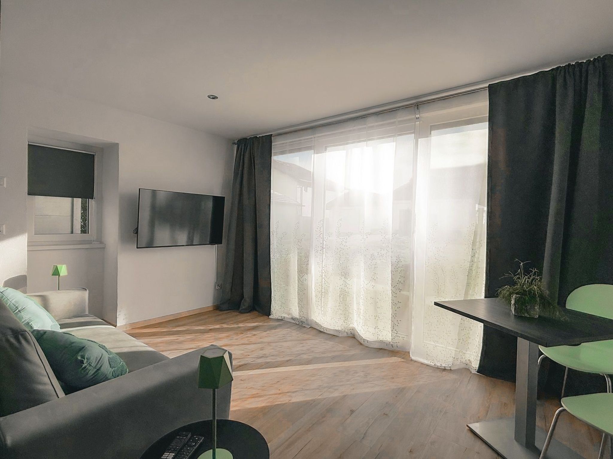 Una sala de estar moderna con una televisión de pantalla plana, un sofá, una mesa de centro y un comedor con mesa y sillas.