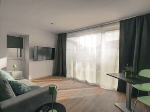 Een moderne woonkamer met een flatscreen televisie, een bank, een salontafel en een eethoek met een tafel en stoelen.