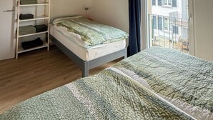 A bedroom with a wooden ceiling, a bed, a wardrobe, and a view of a building outside. - Gîtes - La Clef des Franches, (Saignelegier), by Interhome (Saignelegier)