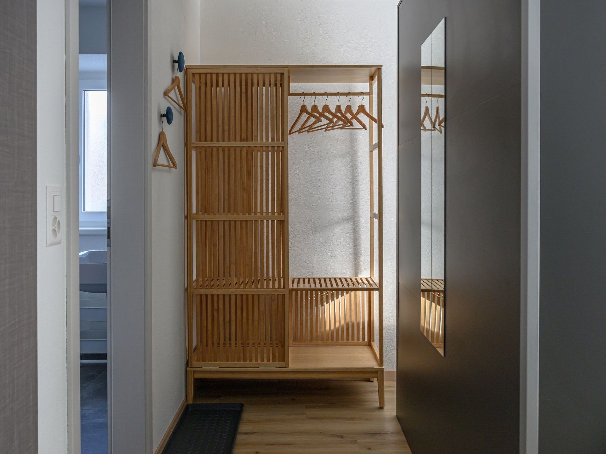 A walk-in closet with wooden sliding doors, a hanging rod, and a mirror on the wall.