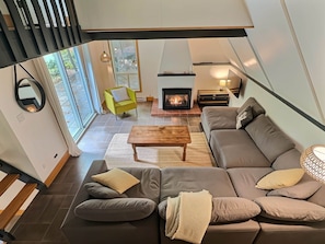 Ein modernes Wohnzimmer mit Kamin, einer Sofagarnitur, einem Couchtisch und einem leuchtend gelben Sessel.