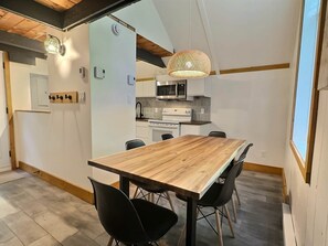 A modern kitchen with white cabinets, a microwave, and a stove. - Chalets Cheribourg - Le 144 - Spa (Orford)