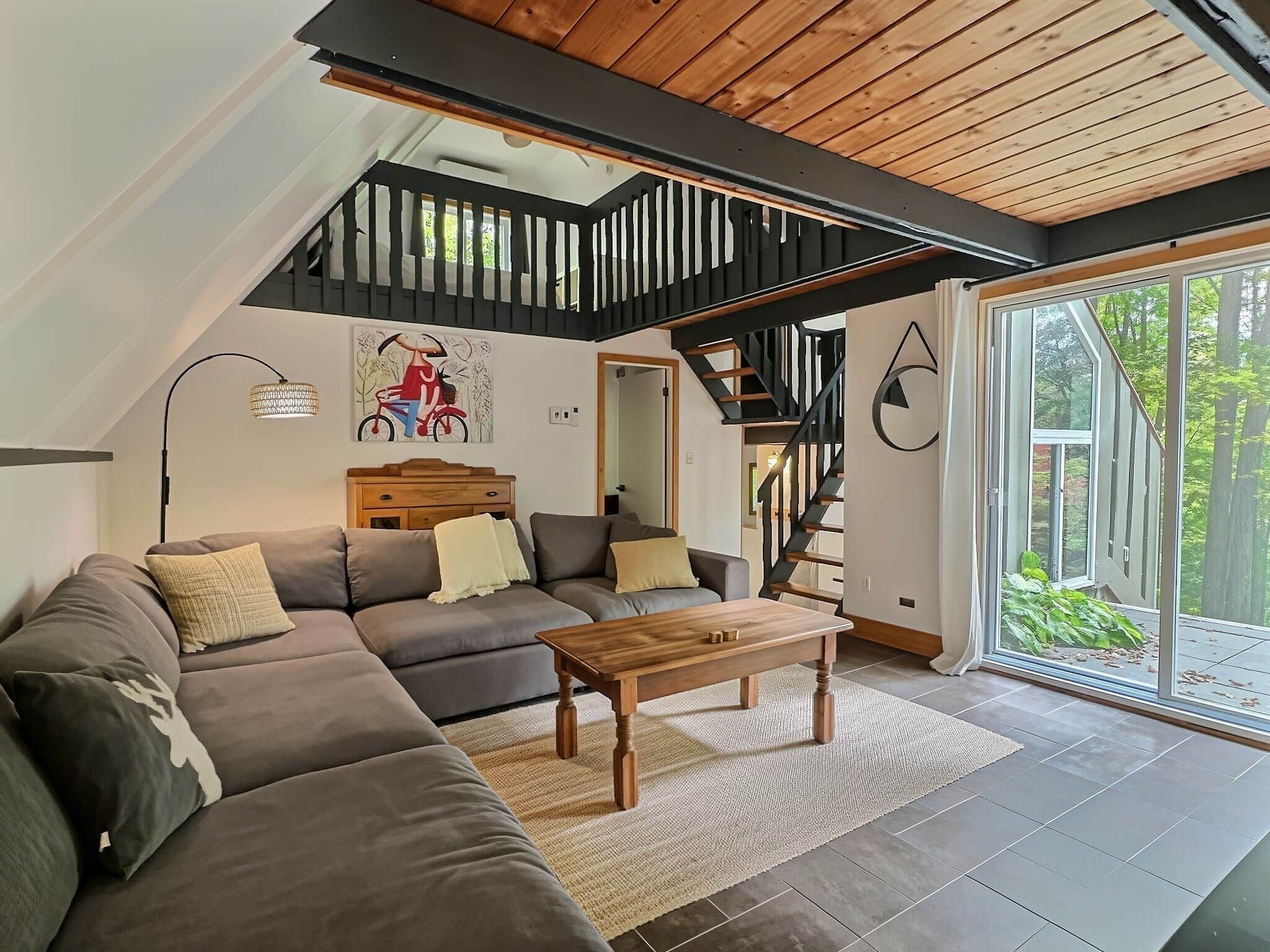 A modern living room with a sectional sofa, a wooden coffee table, and a staircase leading to an upper level.