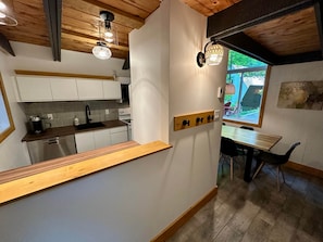 Eine moderne Küche mit weißen Schränken, einer Holzauskładung und einem Fenster mit Blick auf Grünflächen.