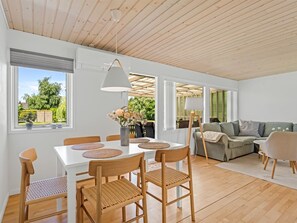 Ein modernes Interieur mit Essbereich, einer Couch und Blick ins Freie.