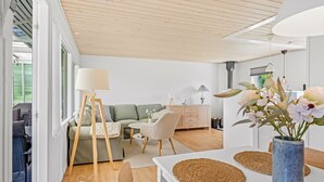 A modern living room with a sofa, a coffee table, a lamp, and a dining area with a table and chairs. - "Gertraud" - 600m from the sea by Interhome (Væggerløse)