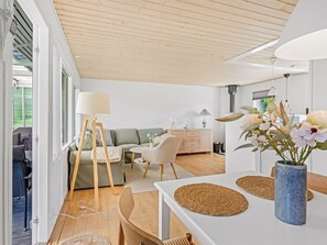 Ein modernes Wohnzimmer mit Sofa, Couchtisch, Lampe und Essbereich mit Tisch und Stühlen.