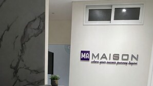 En receptionsdisk med en vägg av marmor och en logotyp för MAISON.