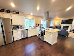 A modern kitchen with white cabinets, stainless steel appliances, and a large island. - 3-bedroom house in wonderful Federal Way with AC for relaxing stays (Federal Way)
