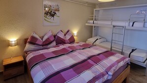 Ein Schlafzimmer mit Etagenbett, Nachttisch, Lampe und Wandregal.