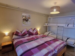 Ein Schlafzimmer mit Etagenbett, Nachttisch, Lampe und Wandregal.