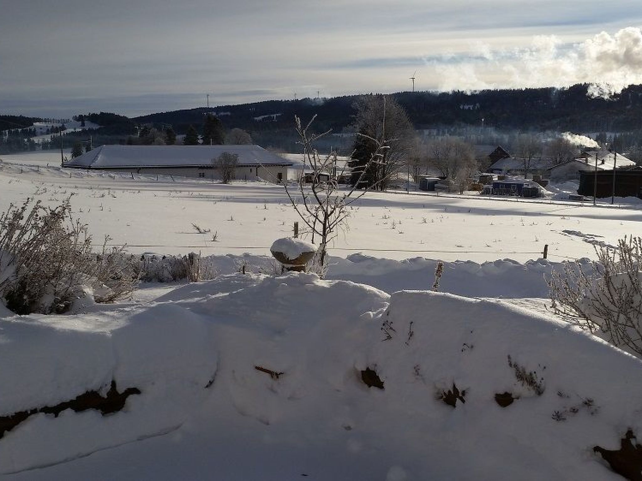Un paysage enneigé avec une grange et des maisons en arrière-plan.