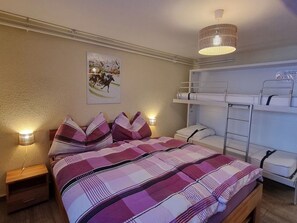 Ein Schlafzimmer mit einem Bett, einem Etagenbett, Nachttischlampen und einem Wandbild.