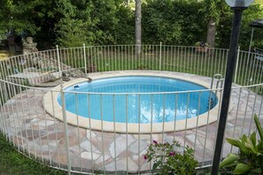 Una piscina circular con un borde de piedra y una valla de metal.
