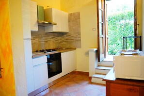 A kitchen with white cabinets, a gas stove, an oven, and a window with a view of greenery. - Vacation Home in Castelfiorentino with 1 bedrooms sleeps 4 (Castelfiorentino)