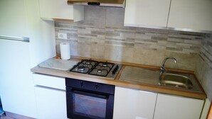 Eine kleine Küche mit Gasherd, Backofen und Spüle.