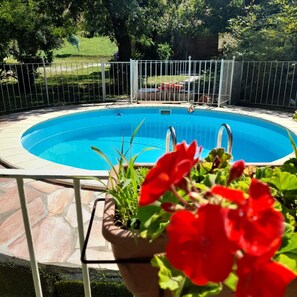 A swimming pool with a surrounding fence, a stone patio, and a potted plant with red flowers. - Vacation Home in Castelfiorentino with 1 bedrooms sleeps 4 (Castelfiorentino)