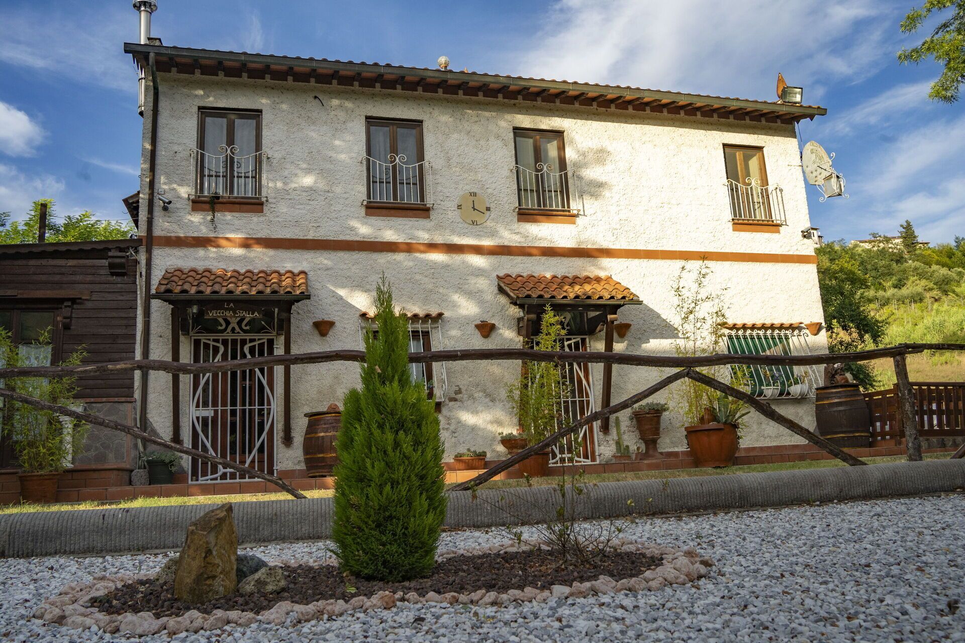 Un edifici de dues plantes amb façana rústica, diverses finestres amb balcons de ferro forjat i una petita antena parabòlica a la teulada.