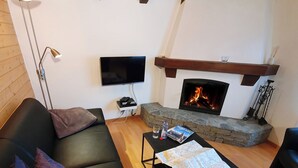 Uma sala de estar com lareira, uma TV de tela plana, um sofá e uma mesa de centro com um mapa.