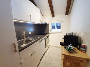 A compact kitchen with a sink, stove, and a window above the countertop. - Bergdohle, (Randa), by Interhome (Randa)