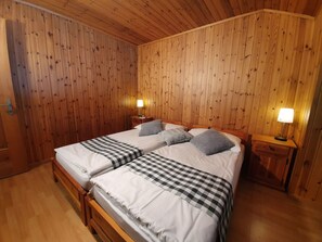 Cama doble con ropa de cama a cuadros en una habitación con paredes y suelos de madera.