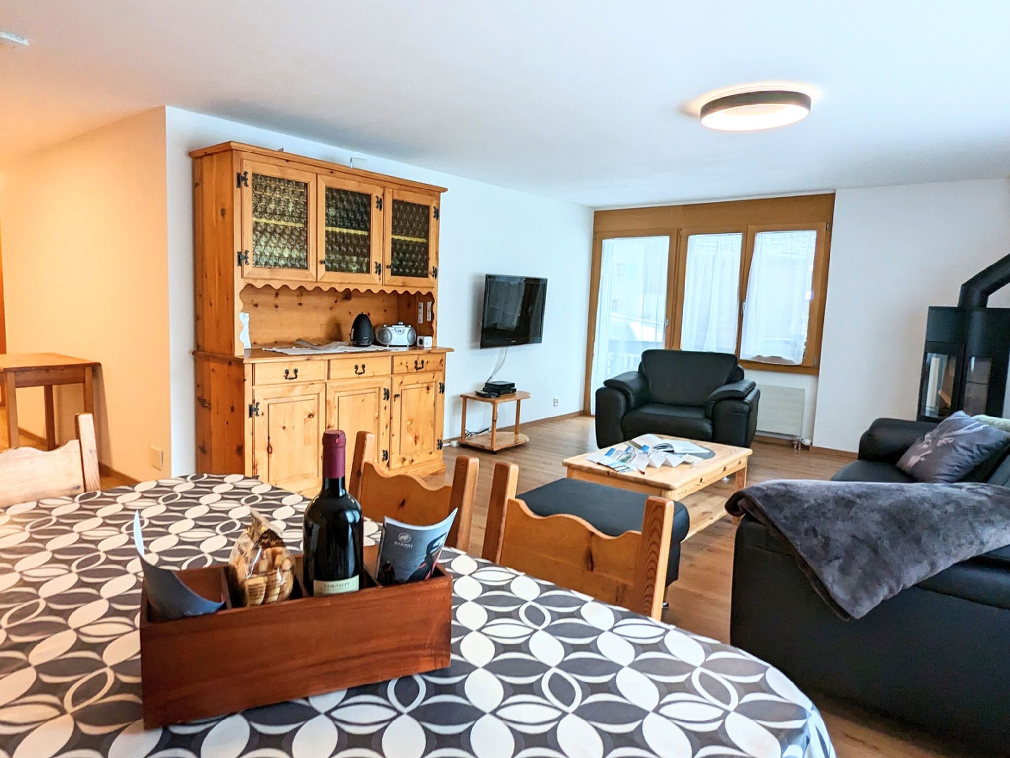 Une pièce confortable avec un lit, une armoire en bois, une télévision, une chaise et un canapé.