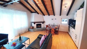 Una sala de estar acogedora con chimenea, mesa de comedor y sofá.