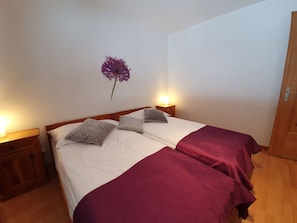 A double bed with two pillows, a bedside table with a lamp, and a wall-mounted flower. - Bergdohle, (Randa), by Interhome (Randa)